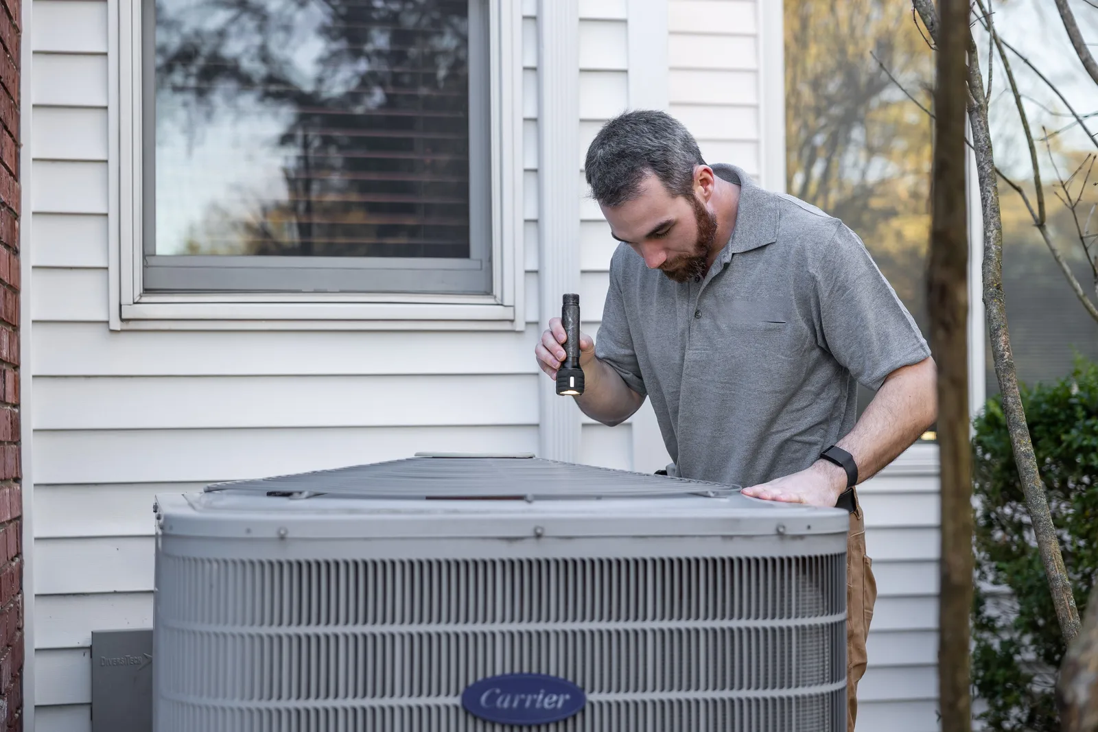 HVAC technician inspecting a residential air conditioning condenser unit